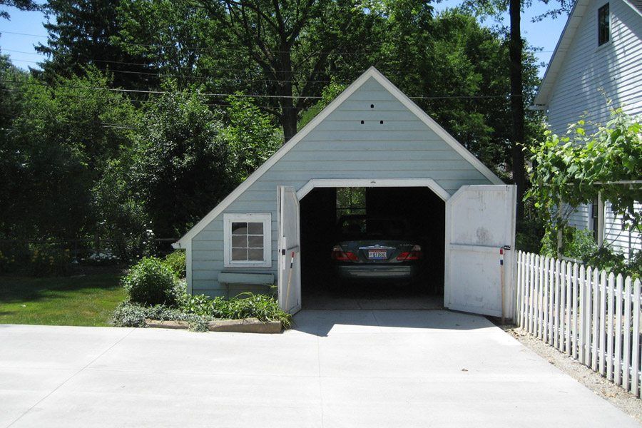 A car is parked in a garage with the doors open
