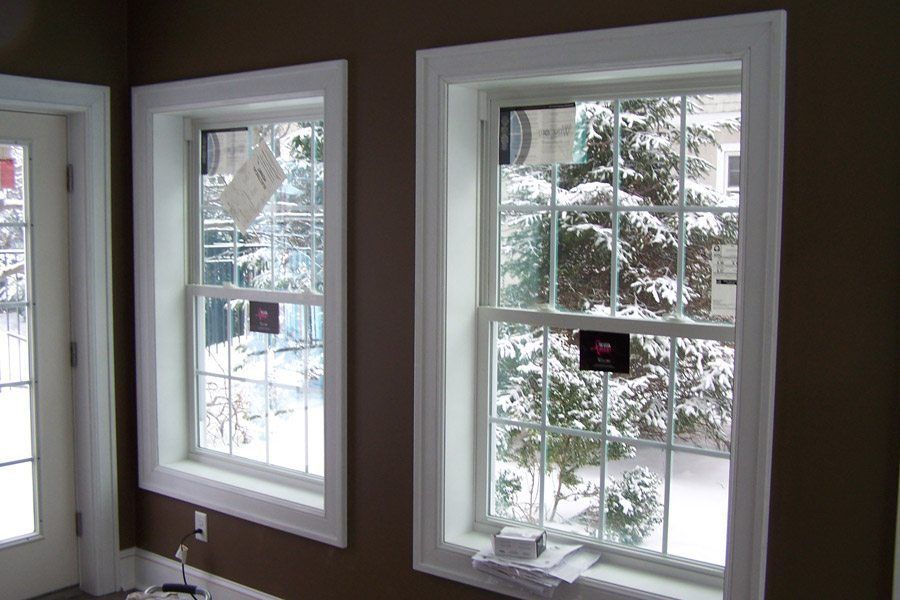 Two windows in a room with snow on the trees outside
