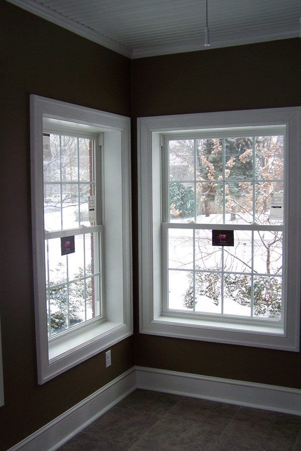 Two windows in a room with brown walls and white trim