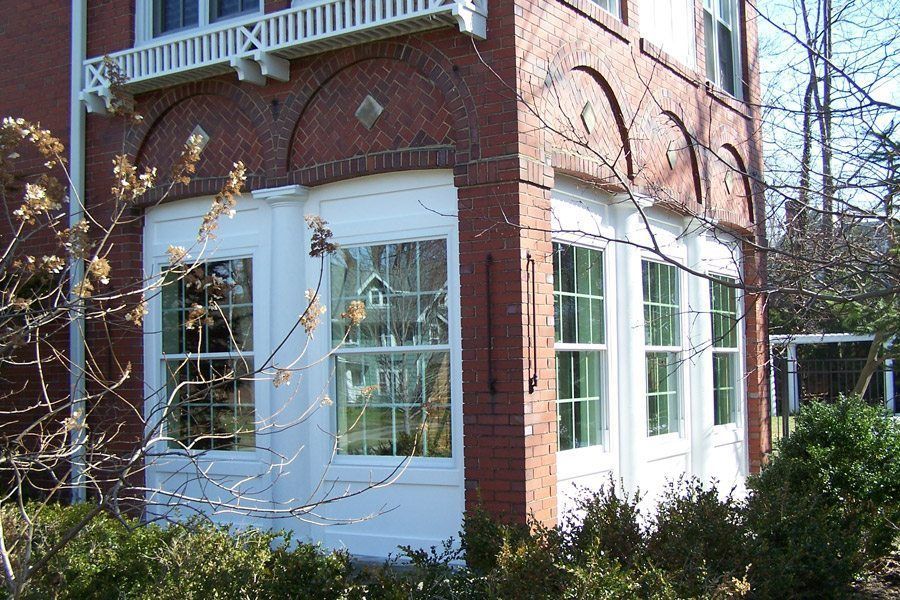 A brick building with white windows and a balcony