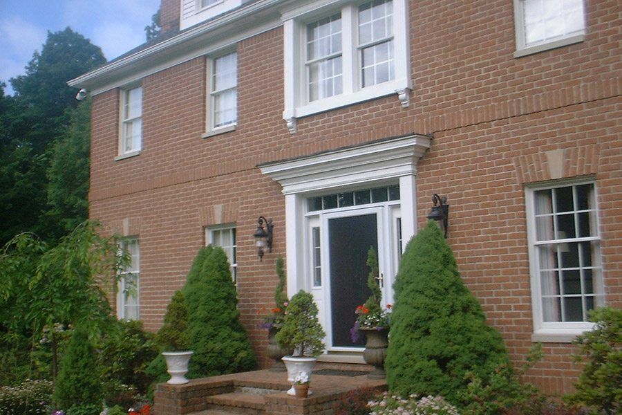 A large brick house with lots of windows and trees in front of it