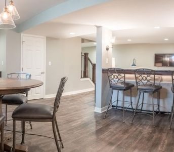 A basement with a table and chairs and a bar.