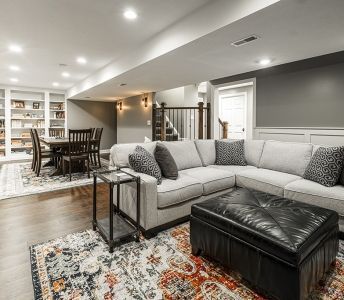 A living room with a couch , ottoman , table and chairs.