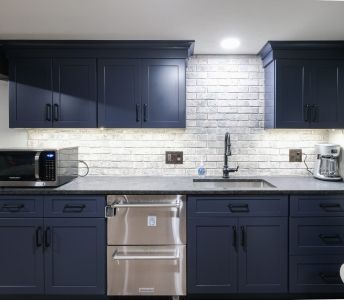 A kitchen with blue cabinets , stainless steel appliances , a sink , and a microwave.