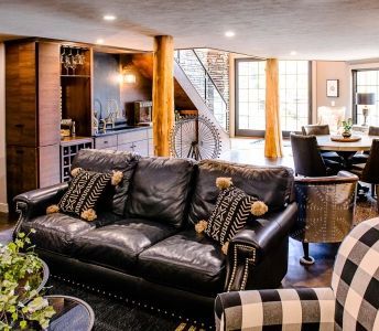 A living room with a black leather couch and a checkered chair