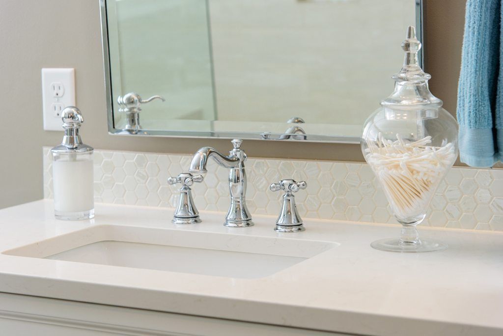A bathroom vanity with a sink , mirror and soap dispenser.