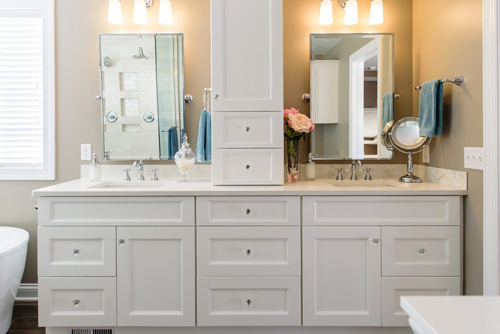 A bathroom with two sinks , a mirror and a tub.