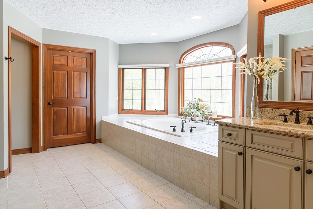 A bathroom with a tub , sink and mirror.