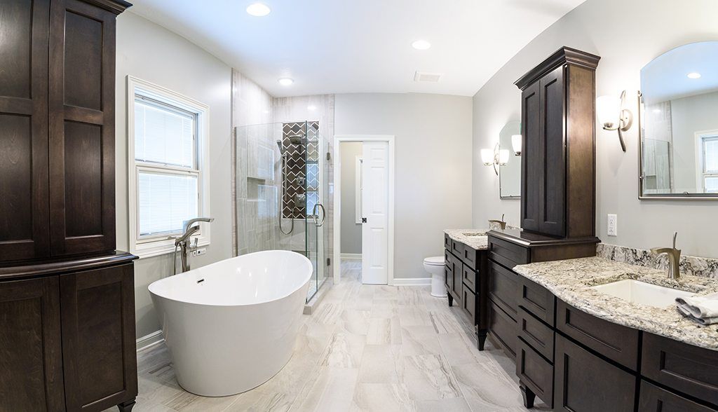 A bathroom with a tub , sinks , cabinets and a walk in shower.
