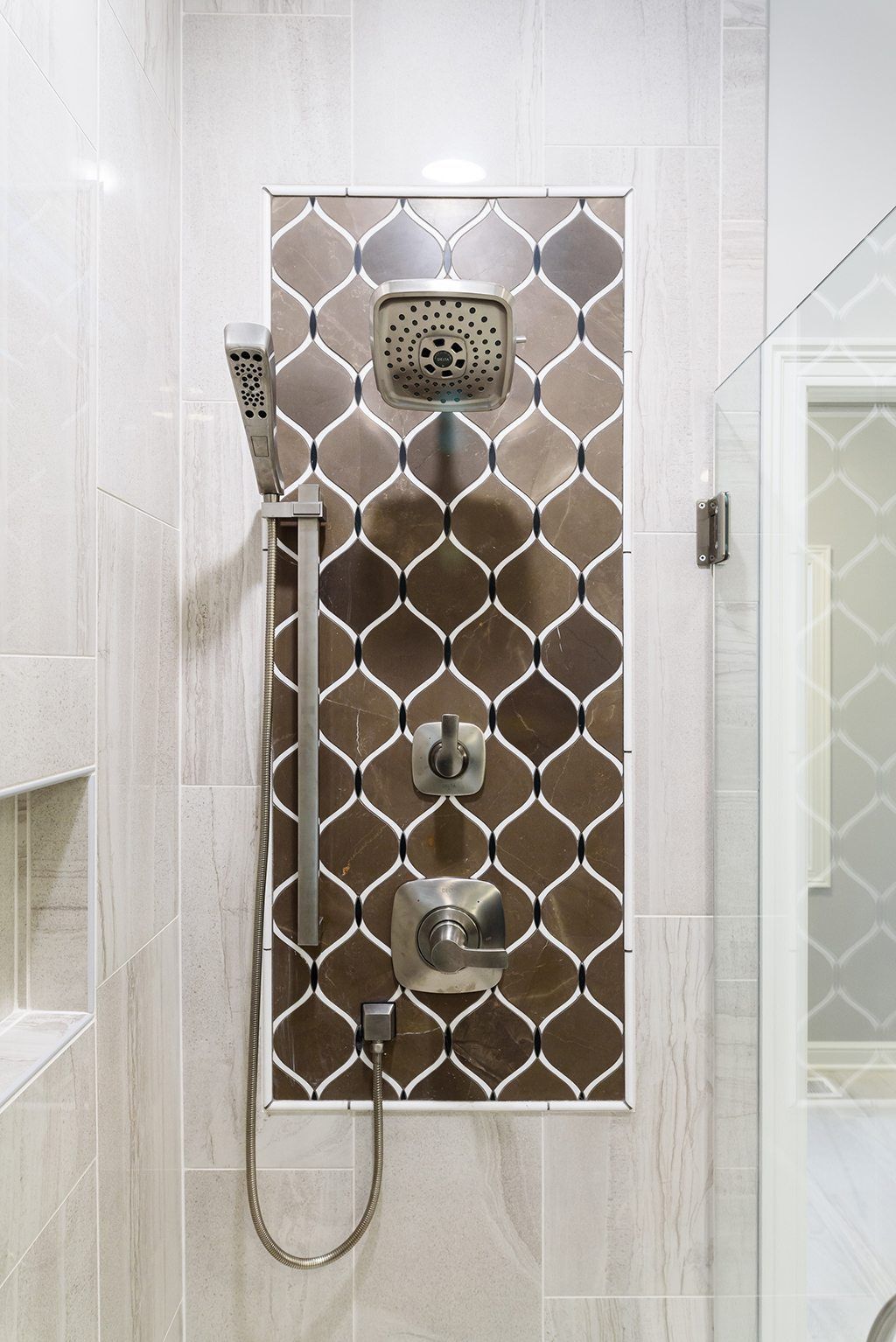 A shower head in a bathroom with a tiled wall.