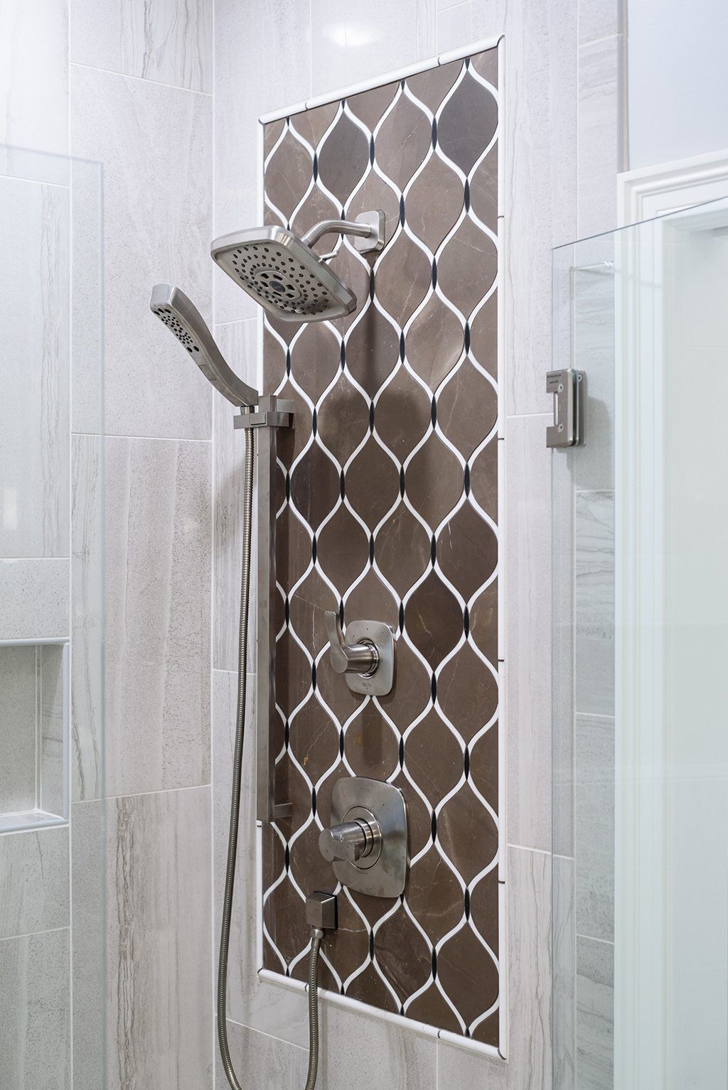 A bathroom with a shower head and a tiled wall.