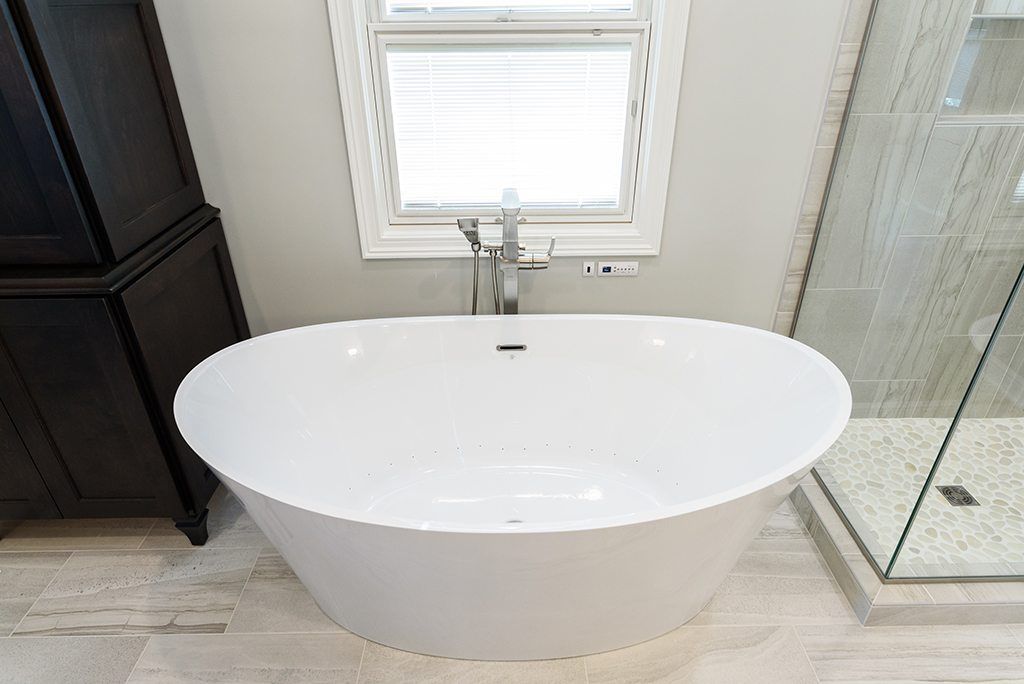 A white bathtub is sitting in a bathroom next to a window.