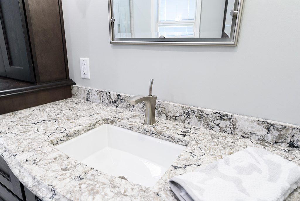 A bathroom sink with a granite counter top and a mirror.