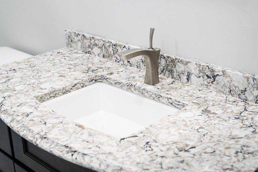 A bathroom sink with a granite counter top and a faucet.