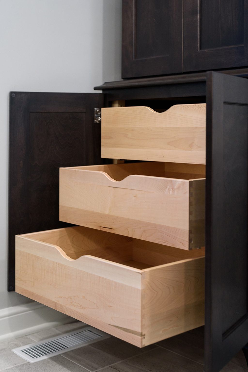 Three wooden drawers are pulled out of a cabinet.