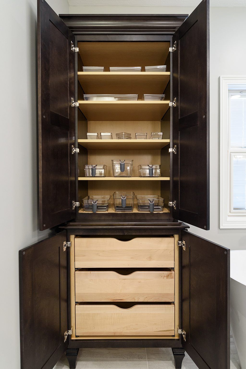 A bathroom cabinet with three drawers and shelves.