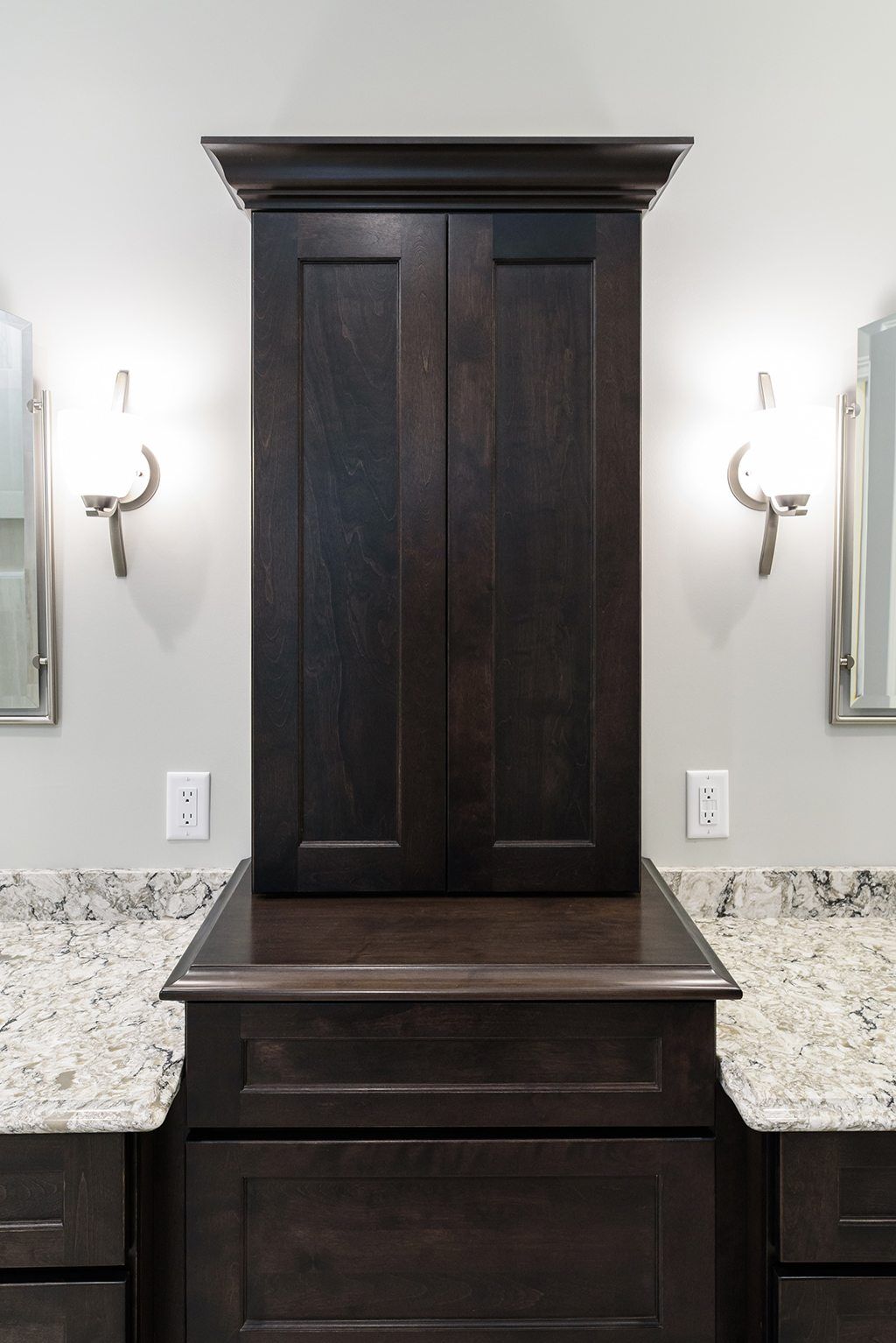A bathroom with two sinks , a cabinet , and two mirrors.