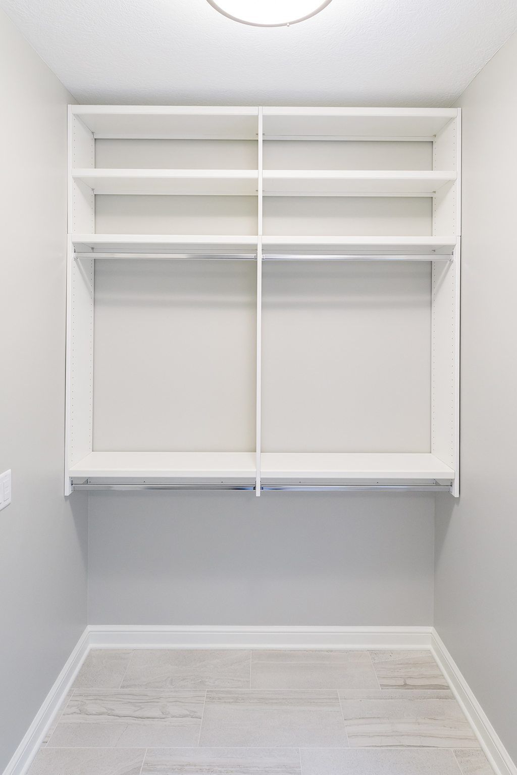 An empty walk in closet with white shelves and a light on the ceiling.