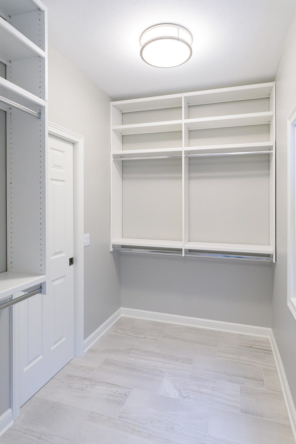 A walk in closet with lots of shelves and a light on the ceiling.