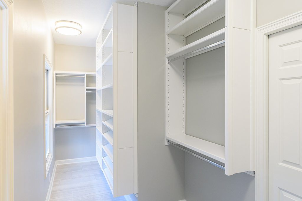 A walk in closet with lots of shelves and hanging clothes.