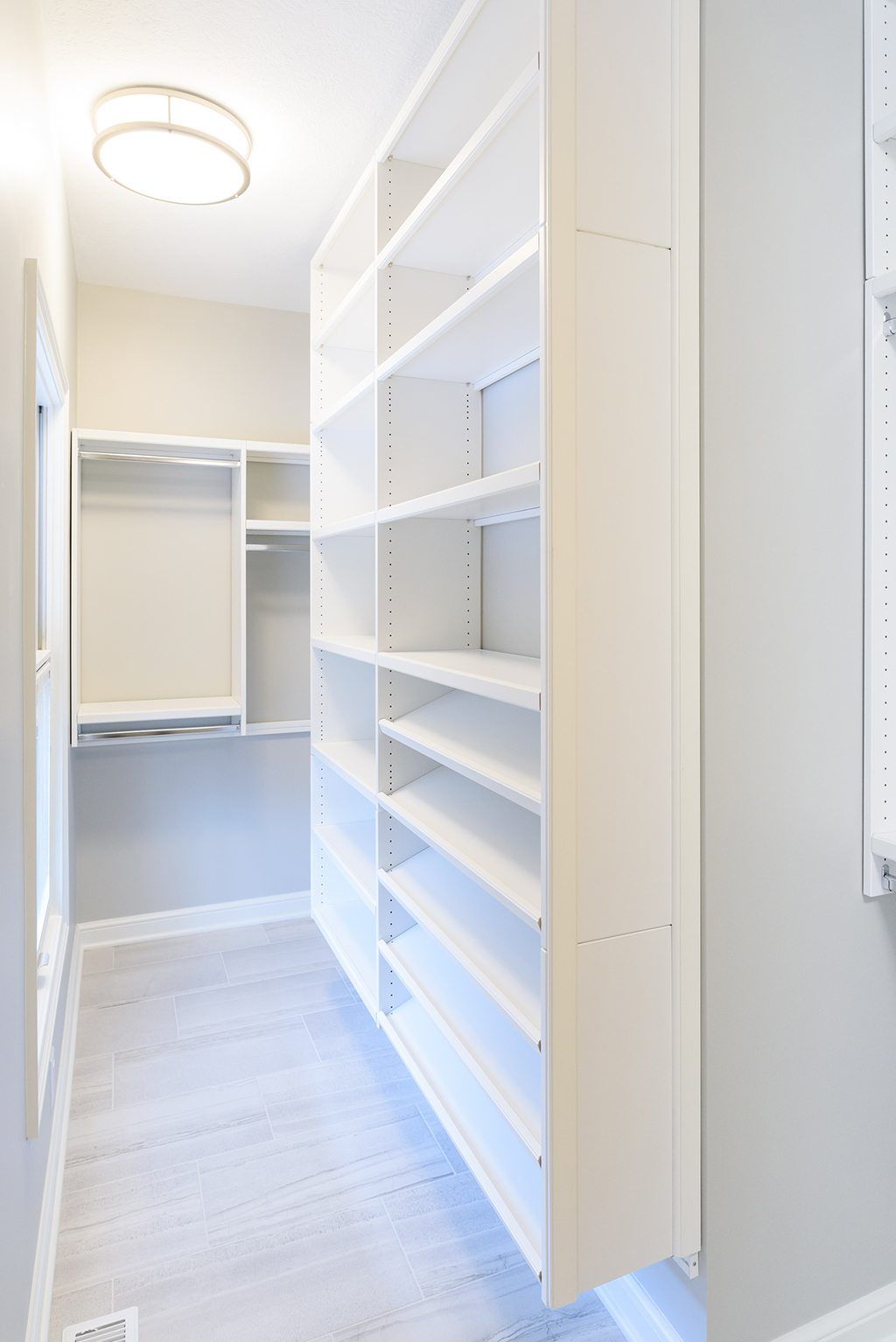 A walk in closet with lots of shelves and a window.