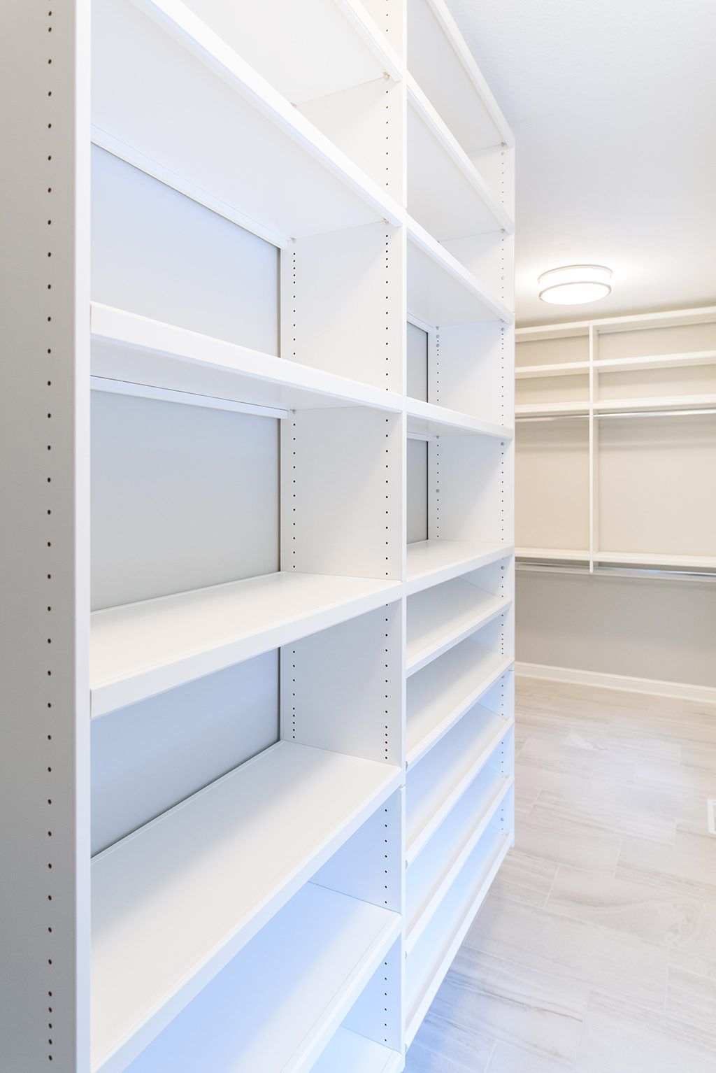 A walk in closet with lots of shelves and a ceiling light.