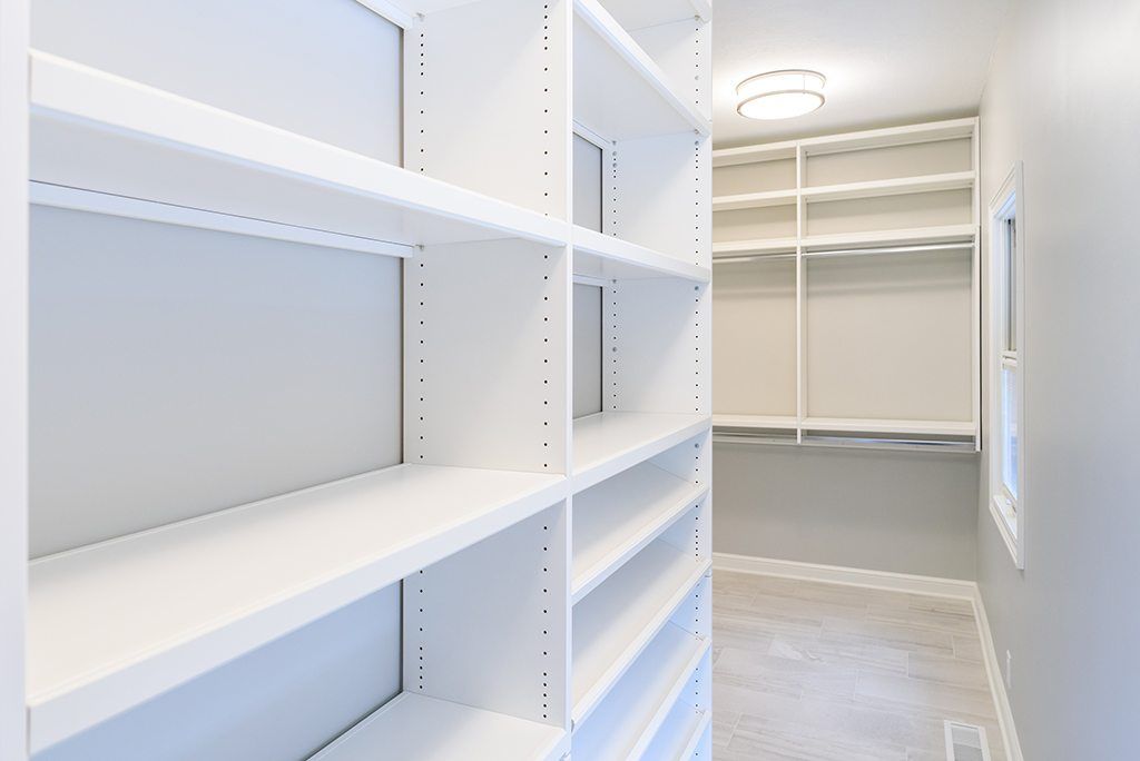 A walk in closet with lots of shelves and a window.