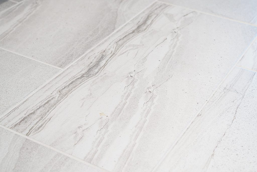 A close up of a white tile floor with a marble texture.