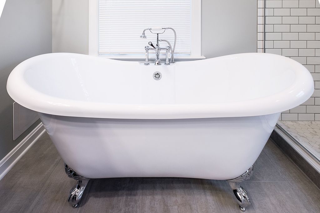 A white bathtub is sitting on a tiled floor in a bathroom.