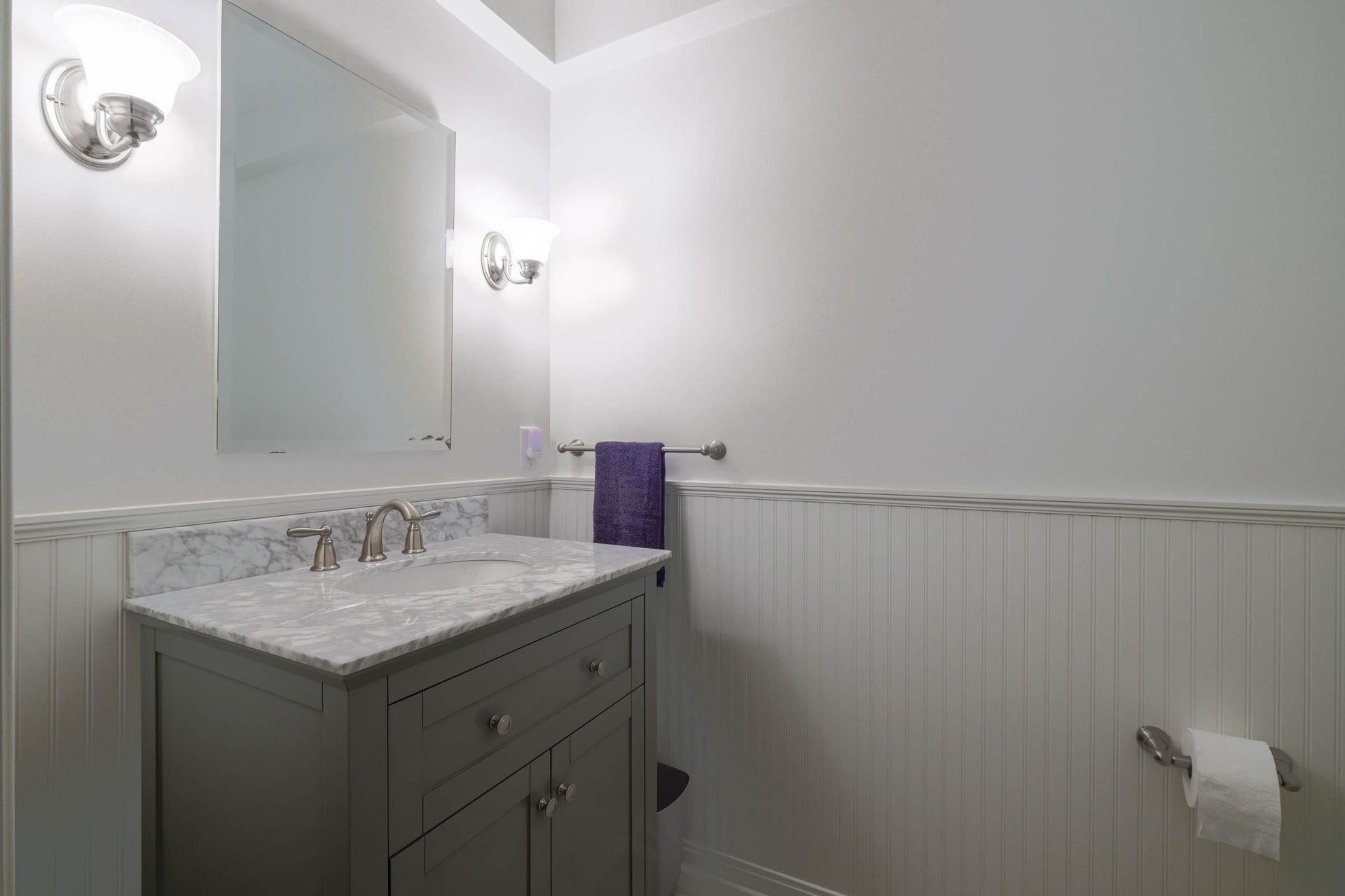 A bathroom with a sink , mirror and towel rack.