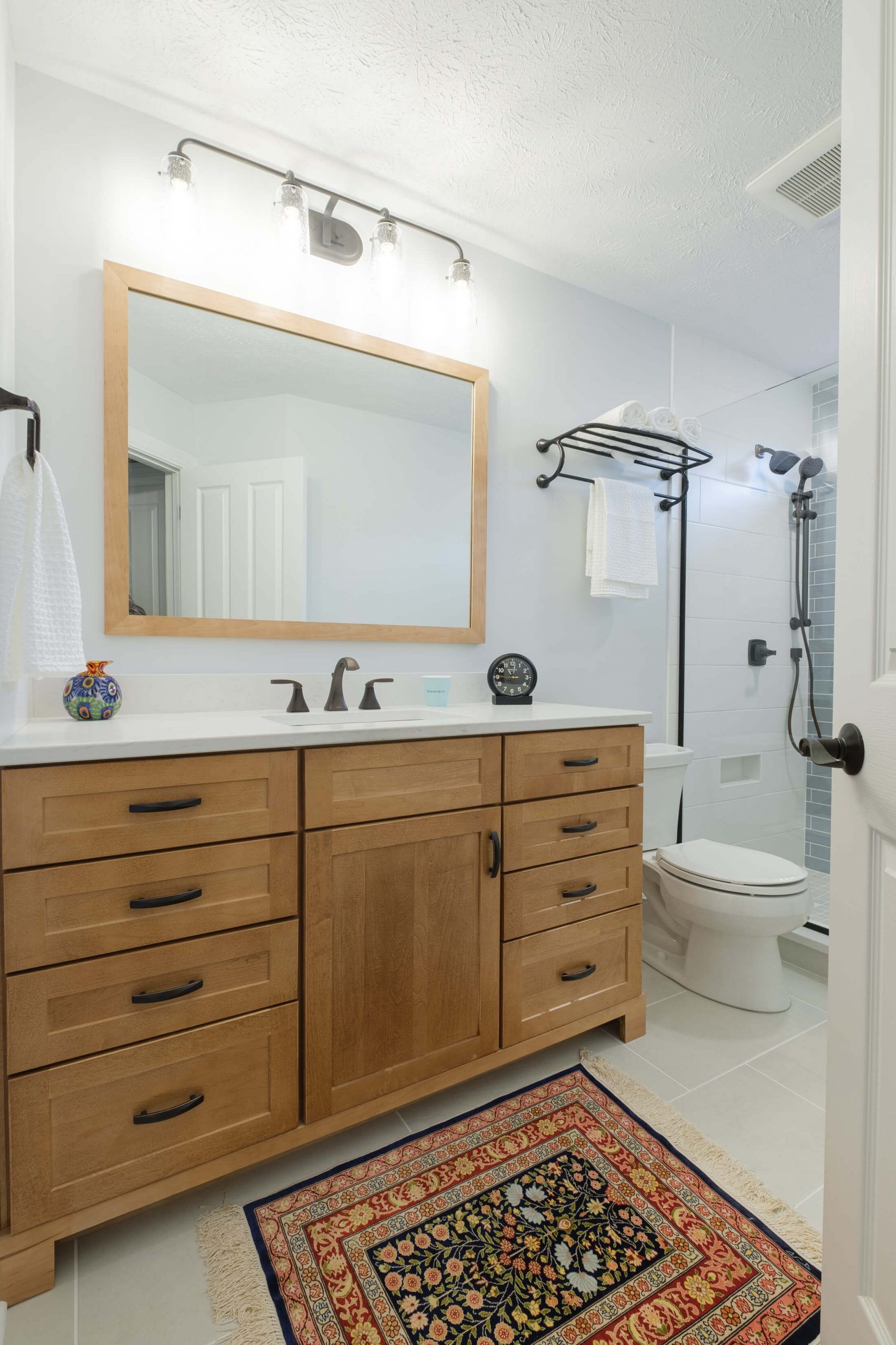 A bathroom with two sinks , a toilet , and a rug.
