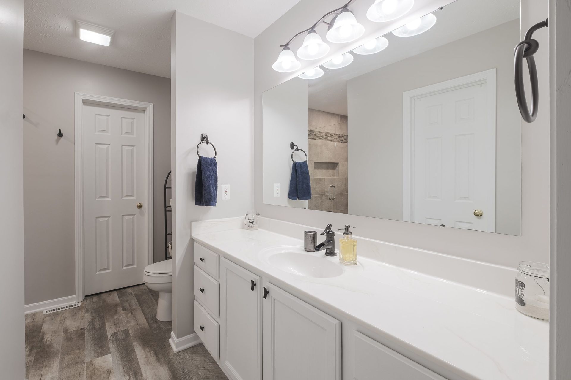 A bathroom with two sinks , a toilet , and a large mirror.
