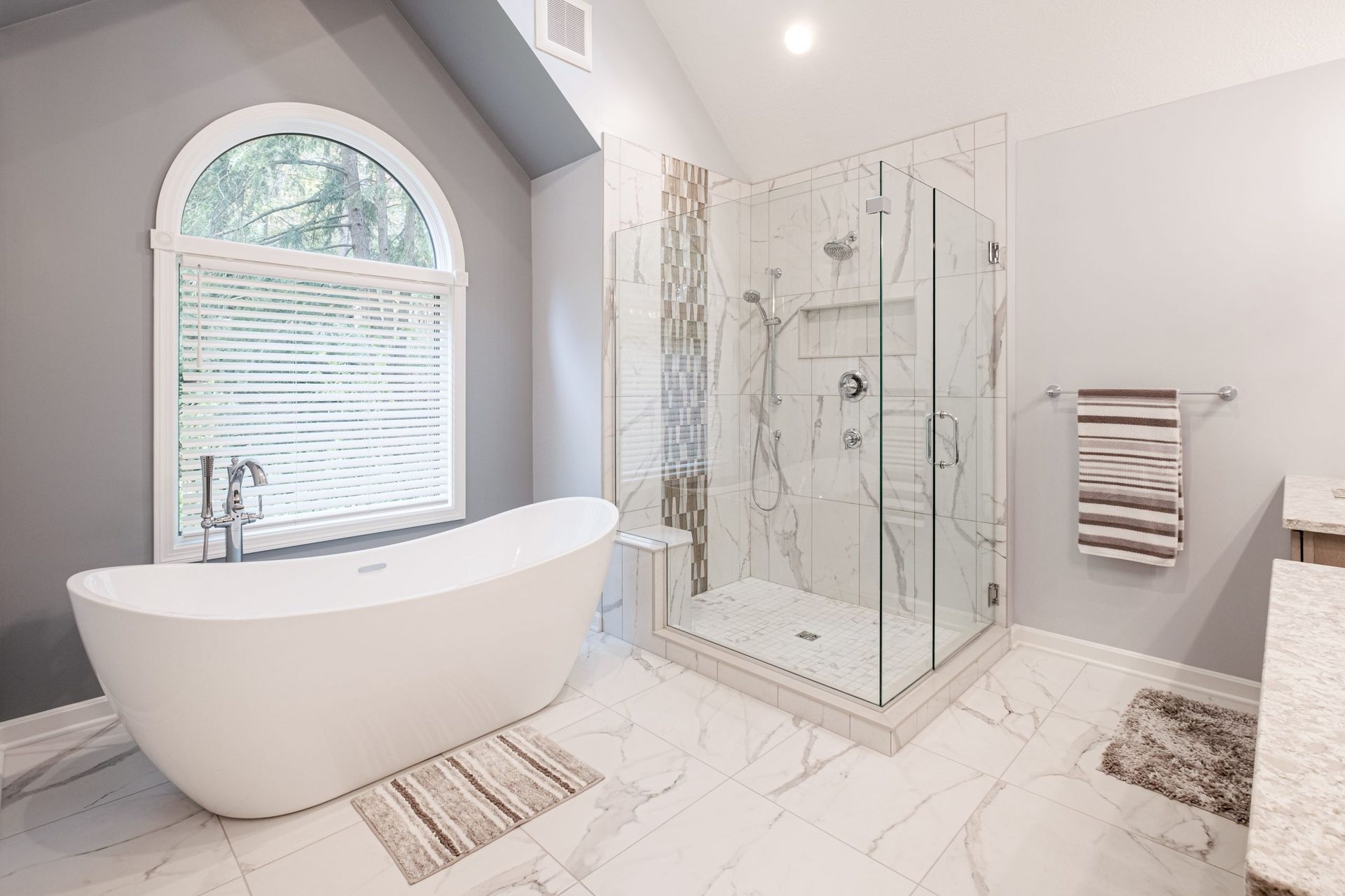 A bathroom with a tub , shower , and window.