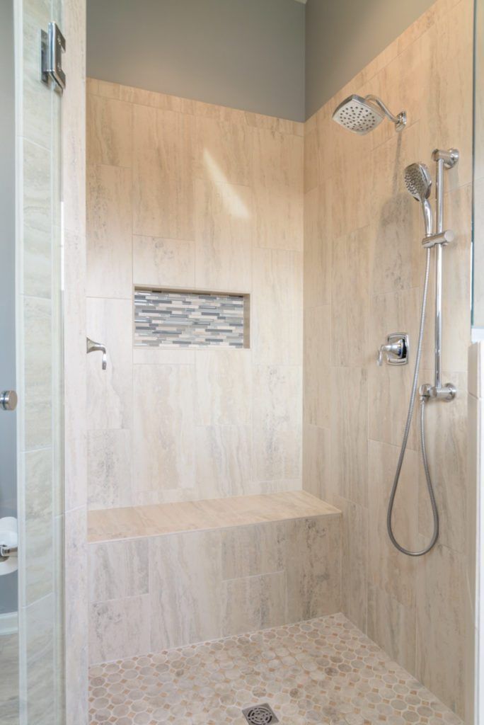 A walk in shower with a bench and a shower head.