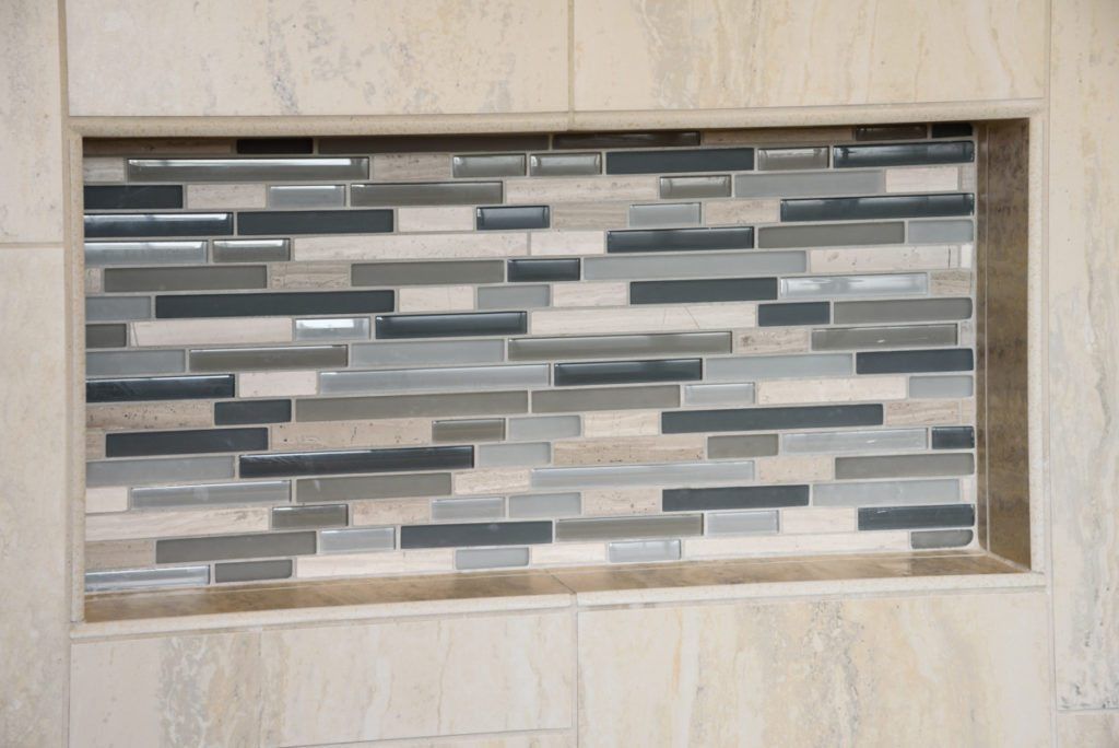 A shower niche with a mosaic tile wall in a bathroom.