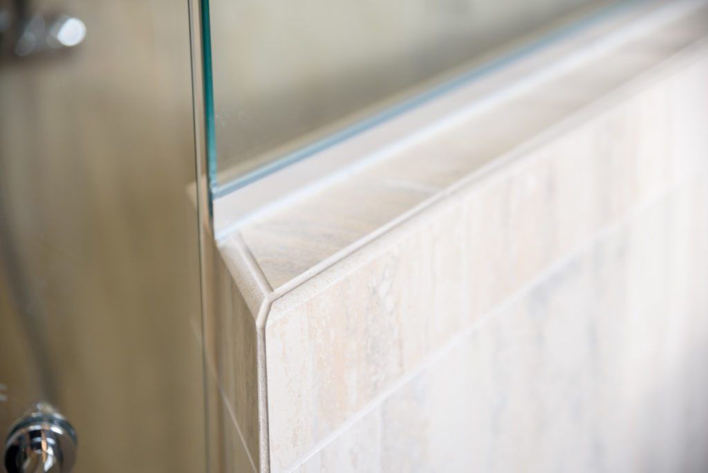 A close up of a bathroom with a shower door and a mirror.