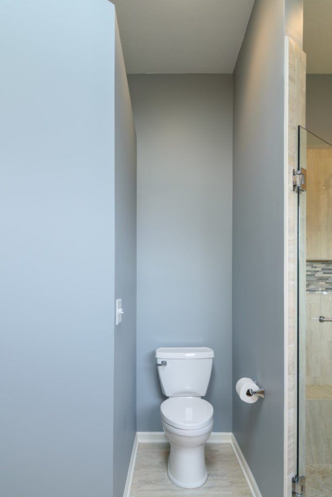 A toilet is sitting in a narrow bathroom next to a shower.