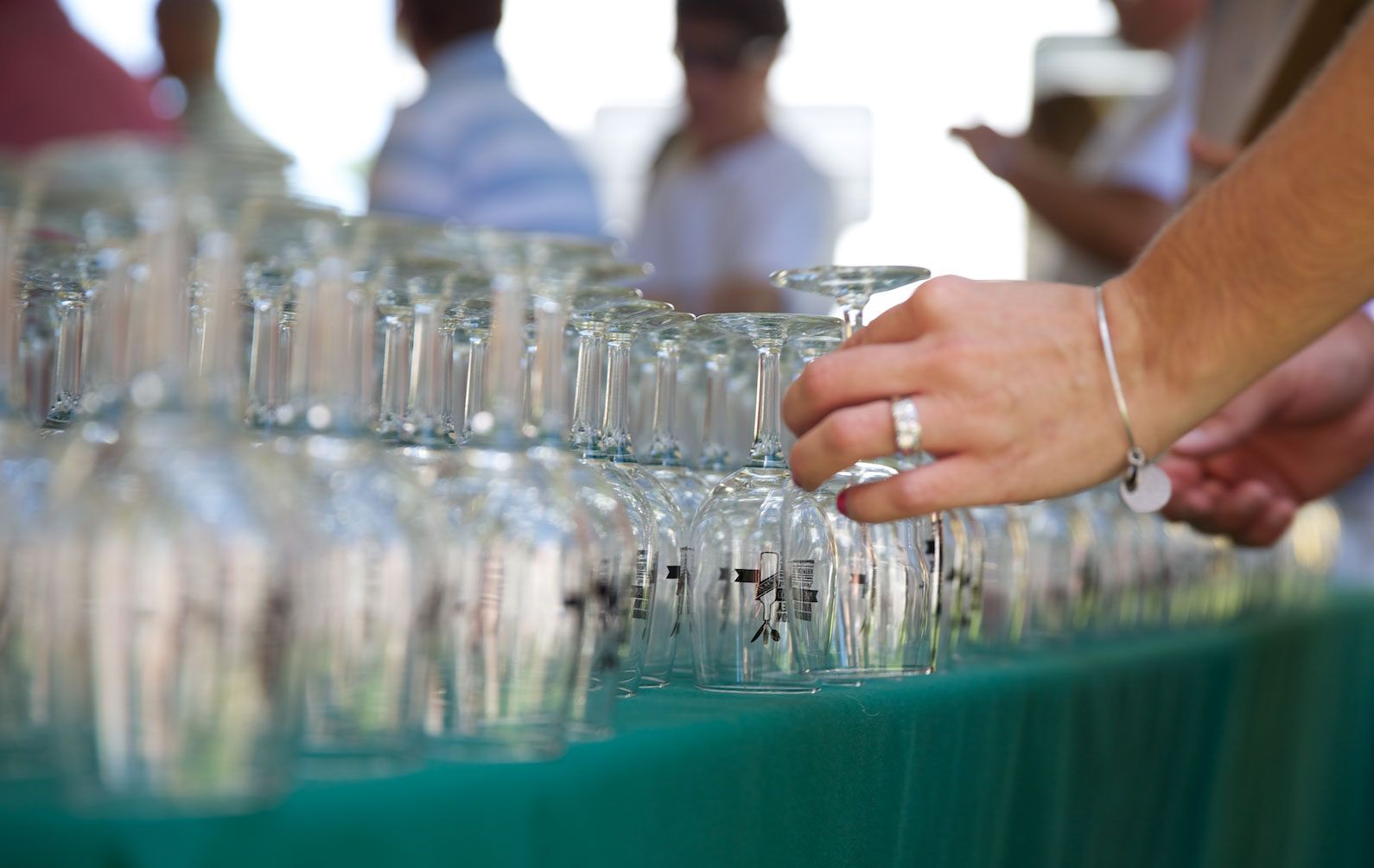 A person is reaching for a wine glass on a table.