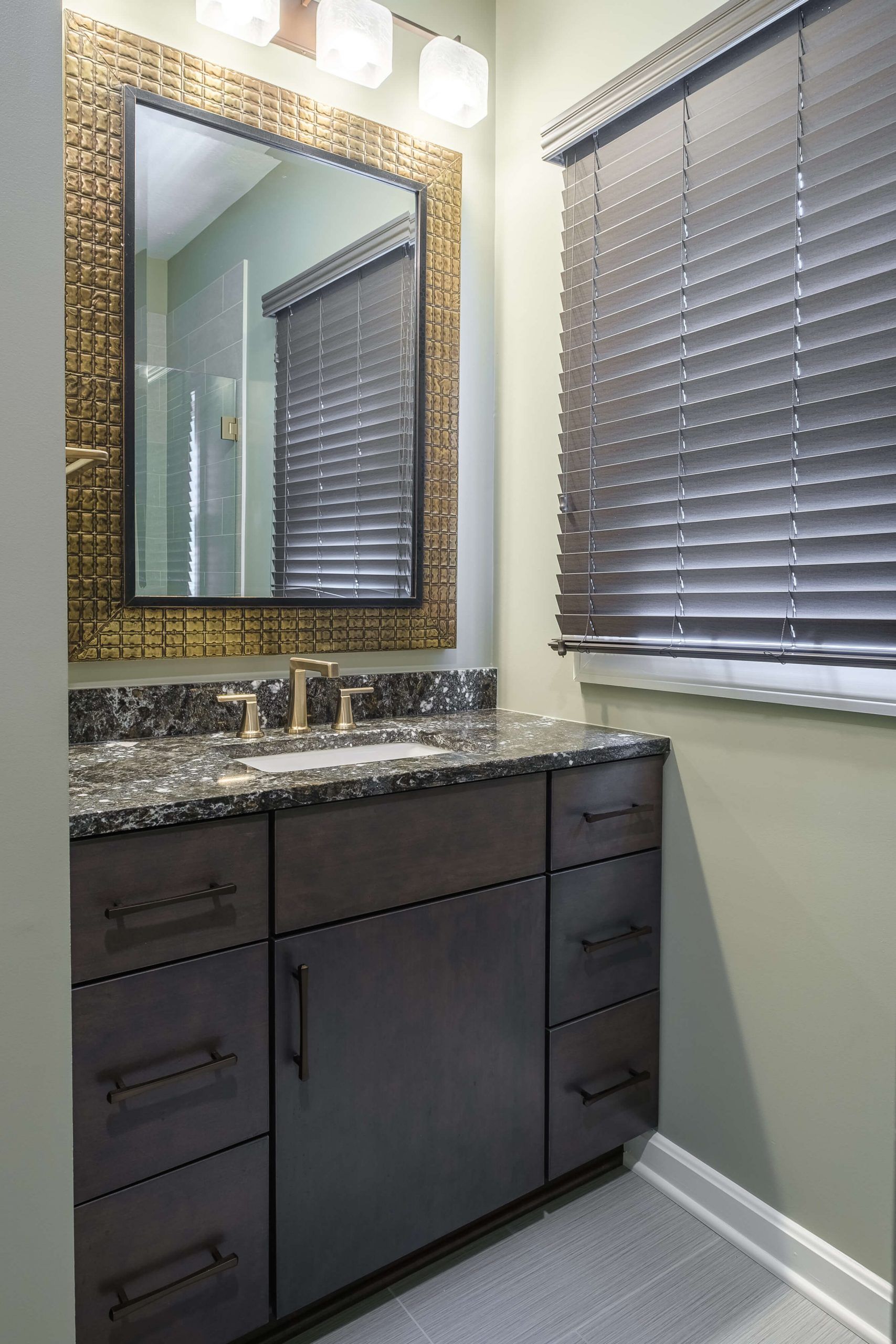 A bathroom with a sink , mirror and window.