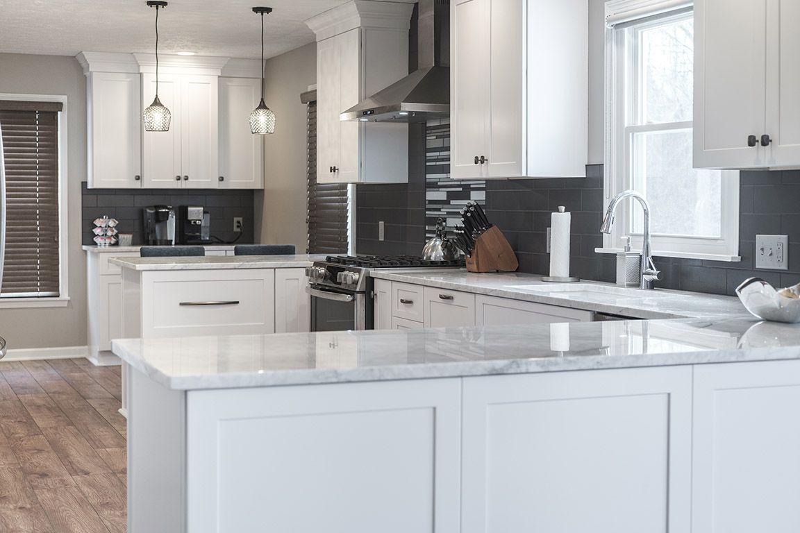 A kitchen with white cabinets , granite counter tops , stainless steel appliances and a large island.