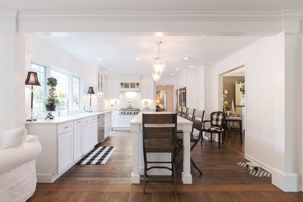 A kitchen with white cabinets , wooden floors , and a large island.