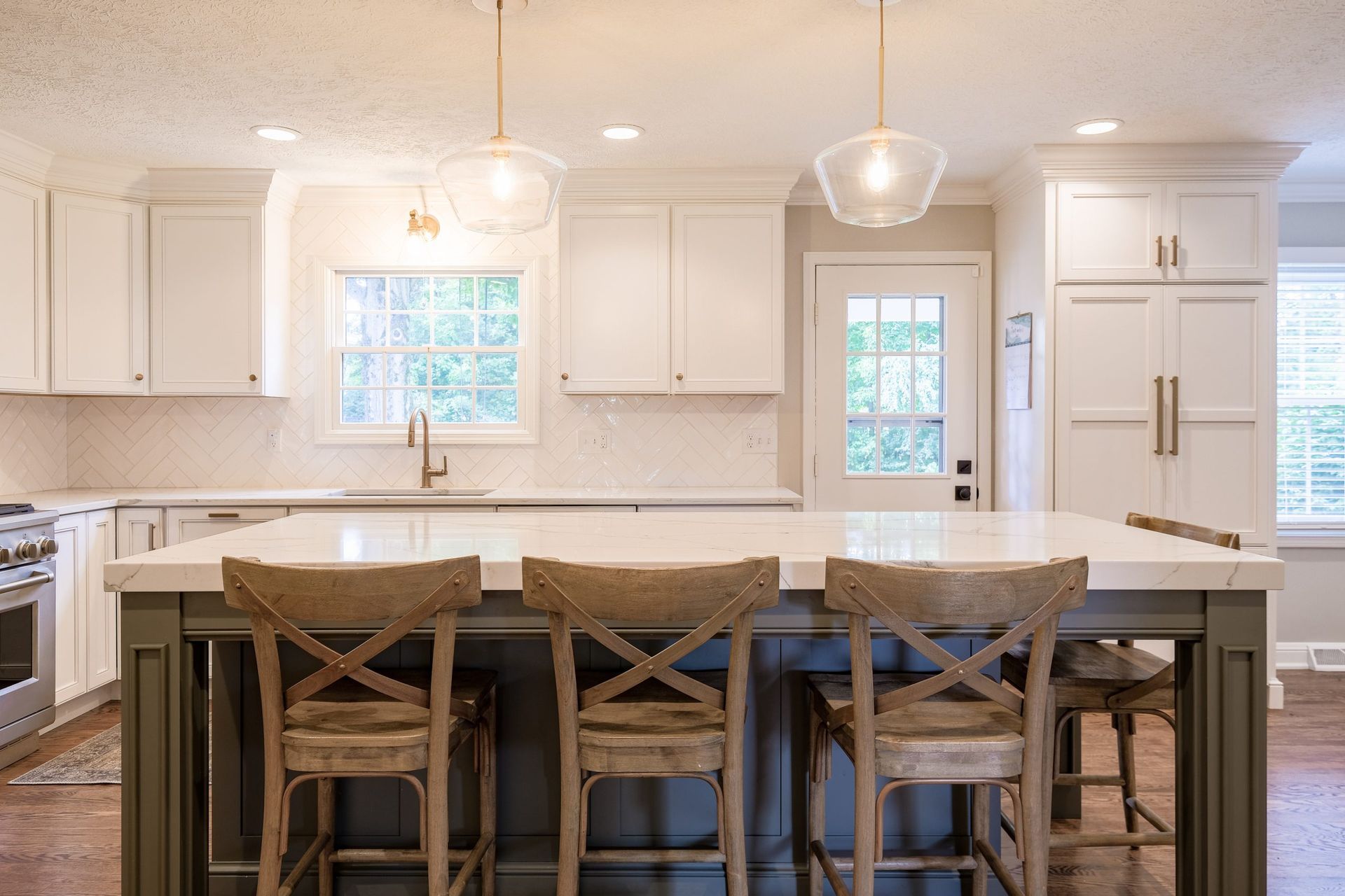 A kitchen with a large island and three chairs.