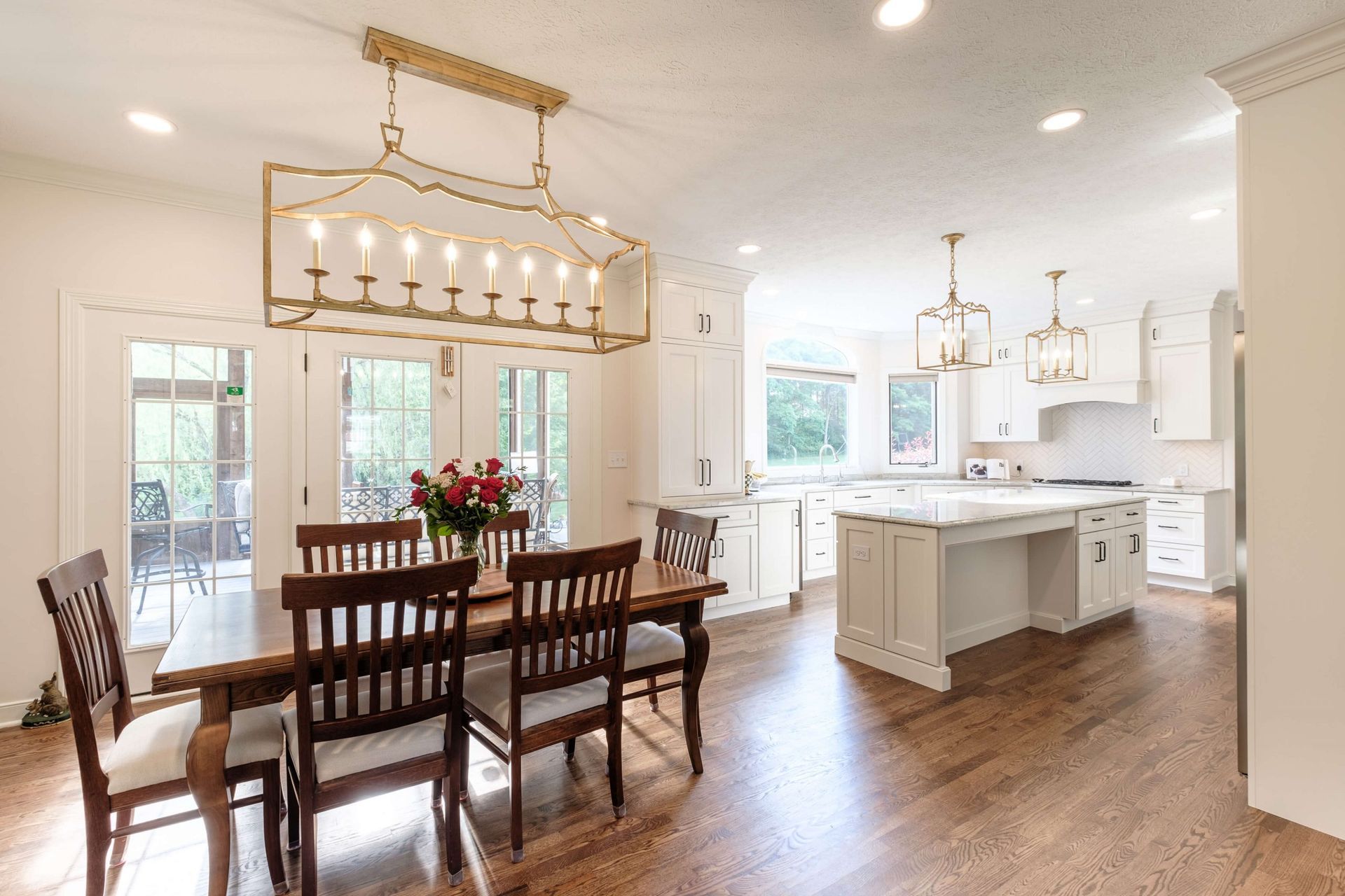 A dining room table and chairs in a kitchen with a chandelier hanging from the ceiling.