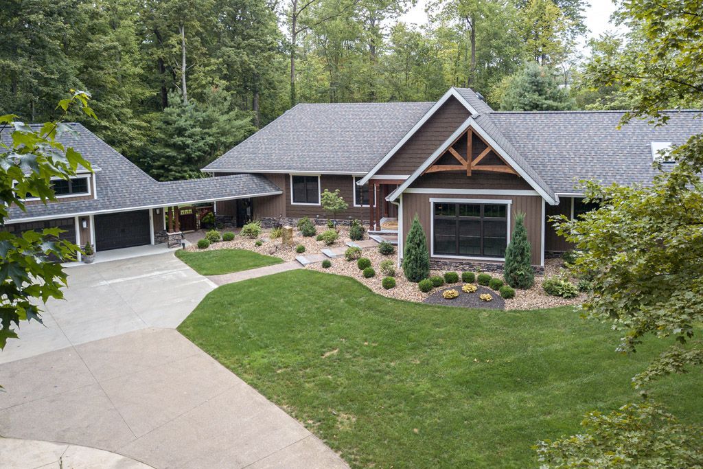 An aerial view of a large house with a driveway leading to it surrounded by trees.