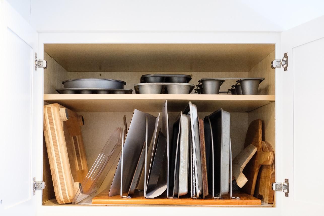 A kitchen cabinet filled with pots and pans and cutting boards.