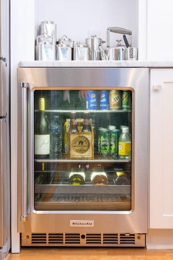 A stainless steel refrigerator with a glass door filled with bottles and cans.