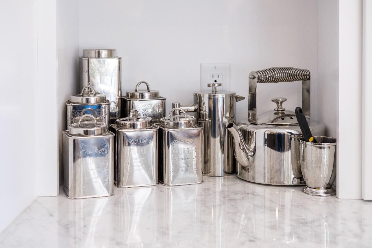 A bunch of silver pots and pans are stacked on top of each other on a counter.