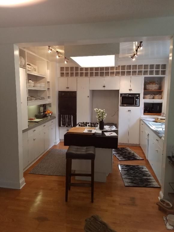 A kitchen with white cabinets and a black island