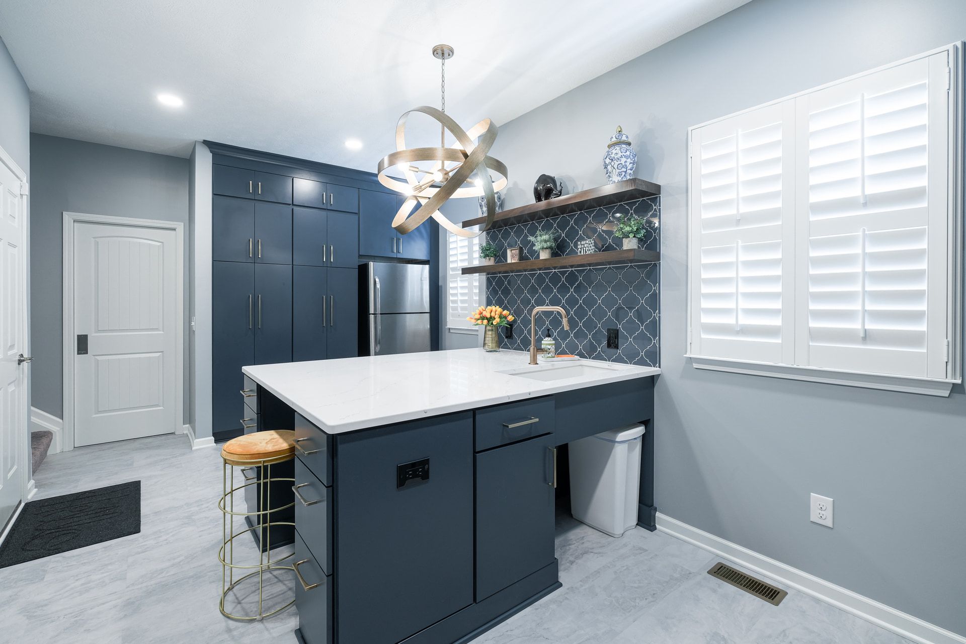 A kitchen with blue cabinets , white counter tops , and a large island.