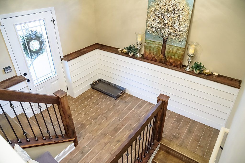 An aerial view of a staircase in a house with a painting of a tree on the wall.
